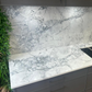 Marble-patterned Eclipsia quartz kitchen countertop with grey cabinets and greenery on the side.