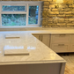 Kitchen with stone wall, window, and taj mahal quartz worktops with ogee edge