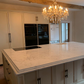 Modern kitchen with Arabescato Cremo Lydia quartz island and chandelier