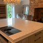 Arabescato Cremo Lydia Quartz kitchen island with chandelier and brick wall in background