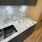 Kitchen counter with marble-like countertop, sink, and dark cabinets.