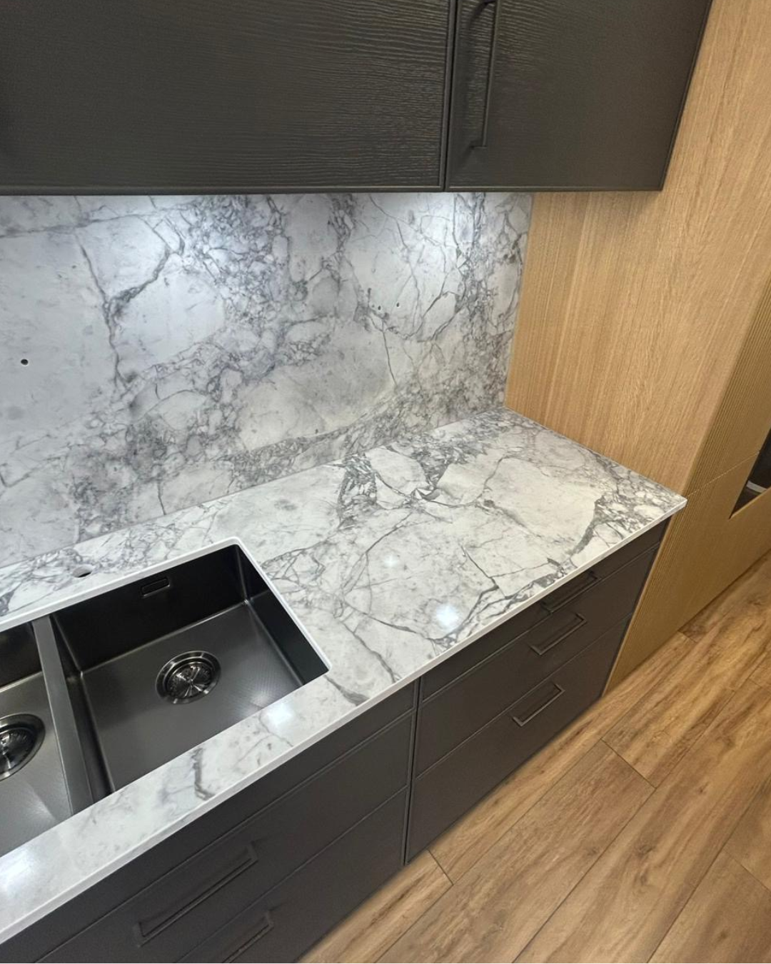 Kitchen counter with marble-like countertop, sink, and dark cabinets.