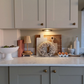 Kitchen counter with decorative items including a wreath, cutting boards, and a small lamp.
