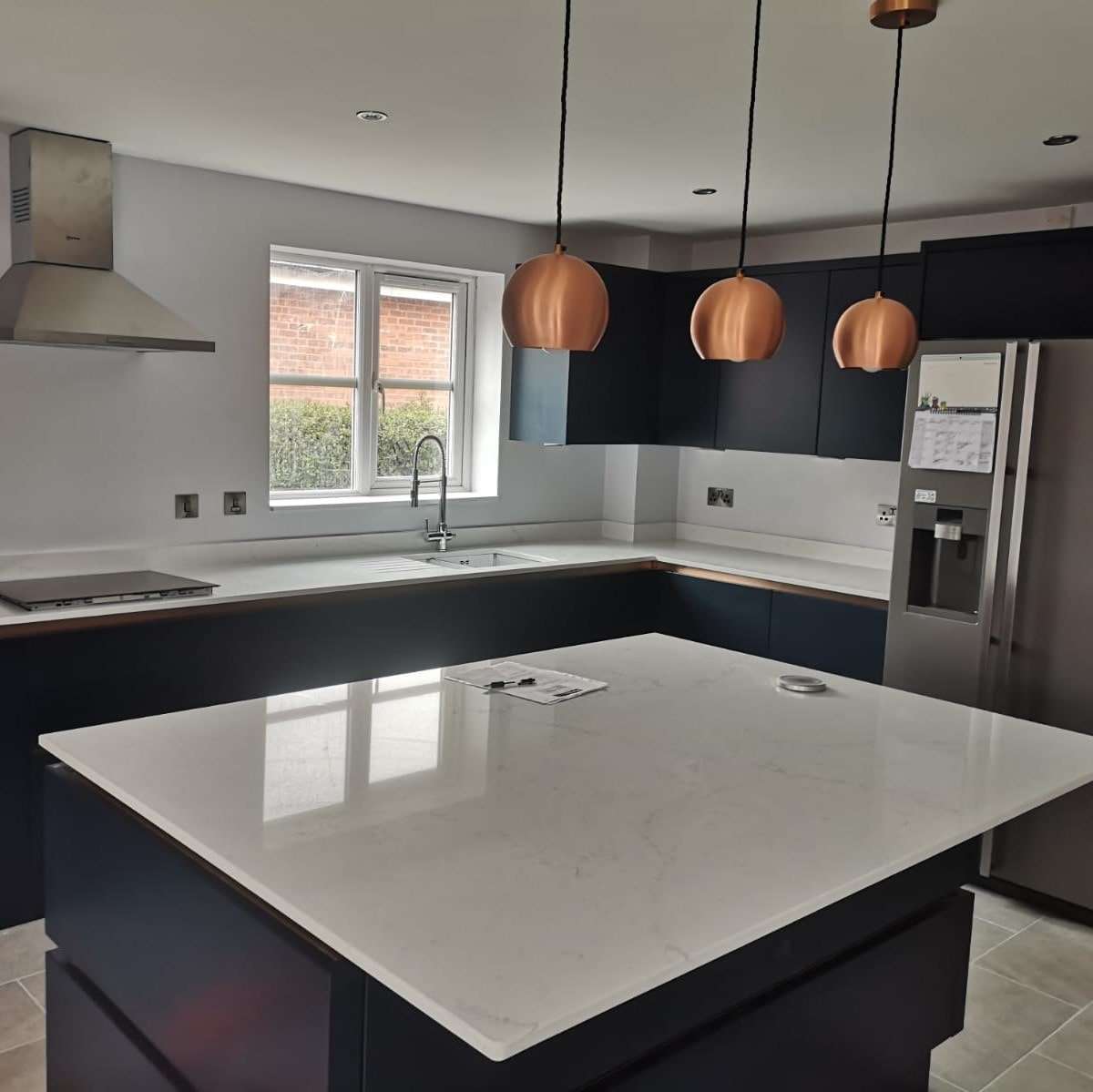 Fugen Avalanche soft white Quartz kitchen worktops and island with faint veining in a grey colour.