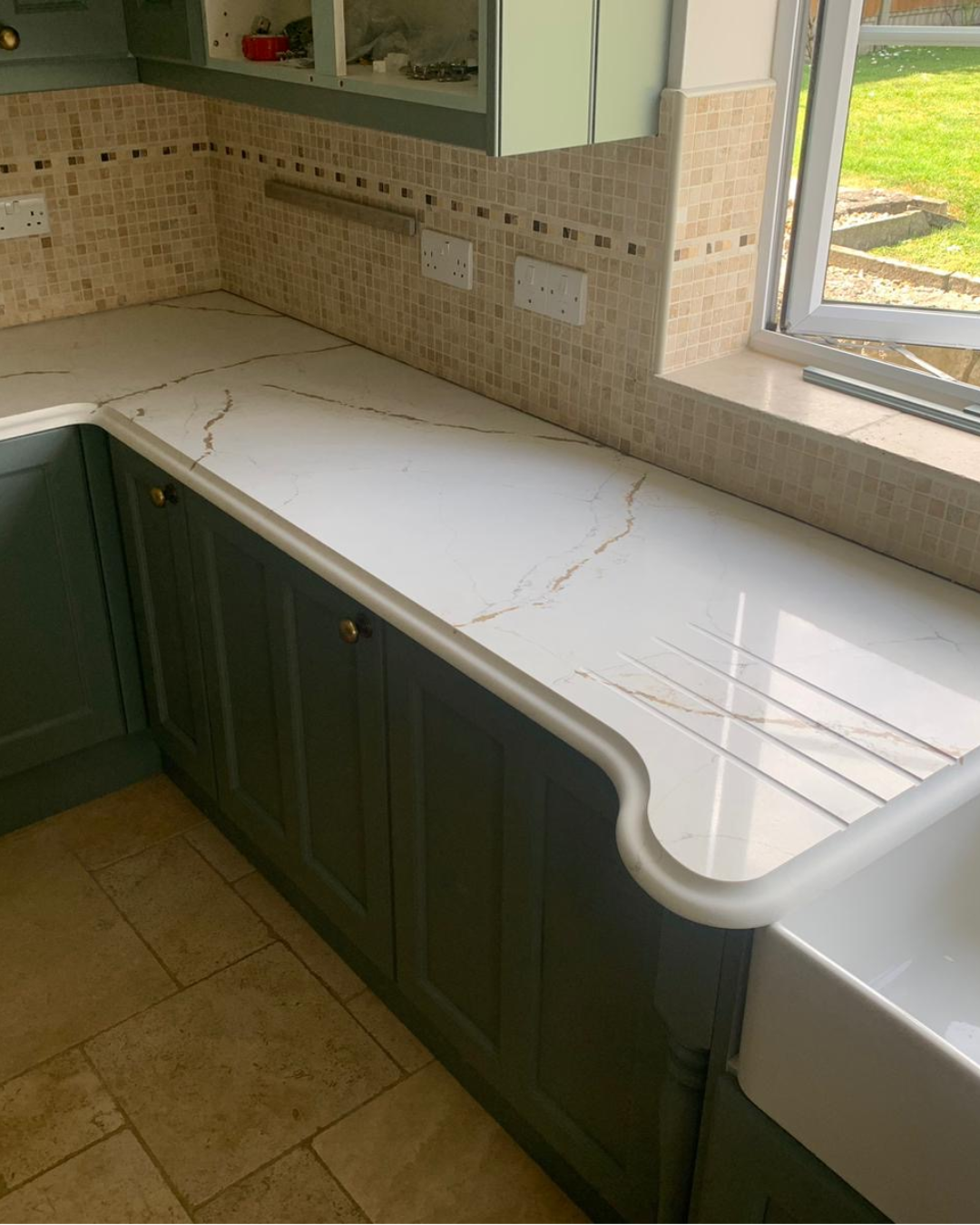 Royal Oro quartz kitchen counter with tiled backsplash and window view