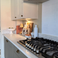 Modern kitchen with gas stove and decorative items on the carrara white quartz worktops