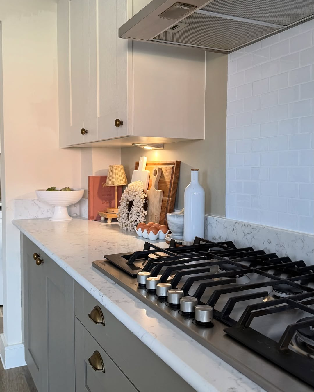 Modern kitchen with gas stove and decorative items on the carrara white quartz worktops