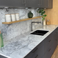Modern kitchen with grey cabinets, Eclipsia quartz worktop, and wooden shelves.