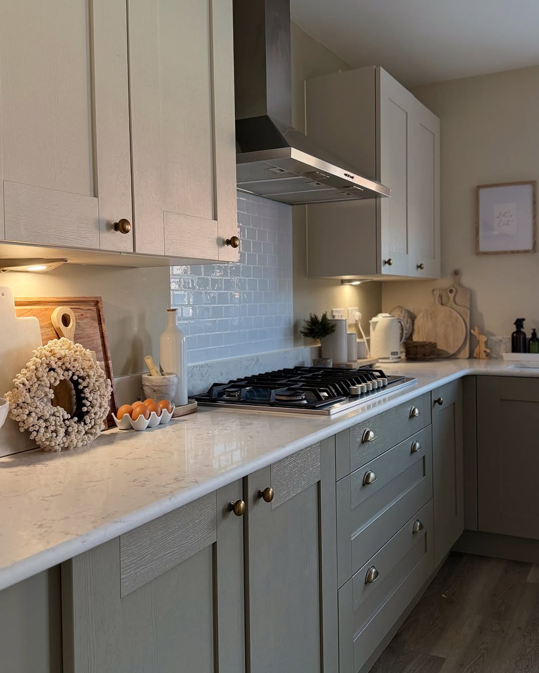 Modern kitchen with light grey cabinets, carrara white quartz worktops and stainless steel appliances.