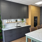 Modern kitchen with grey cabinets, marble effect countertops, and wooden accents.