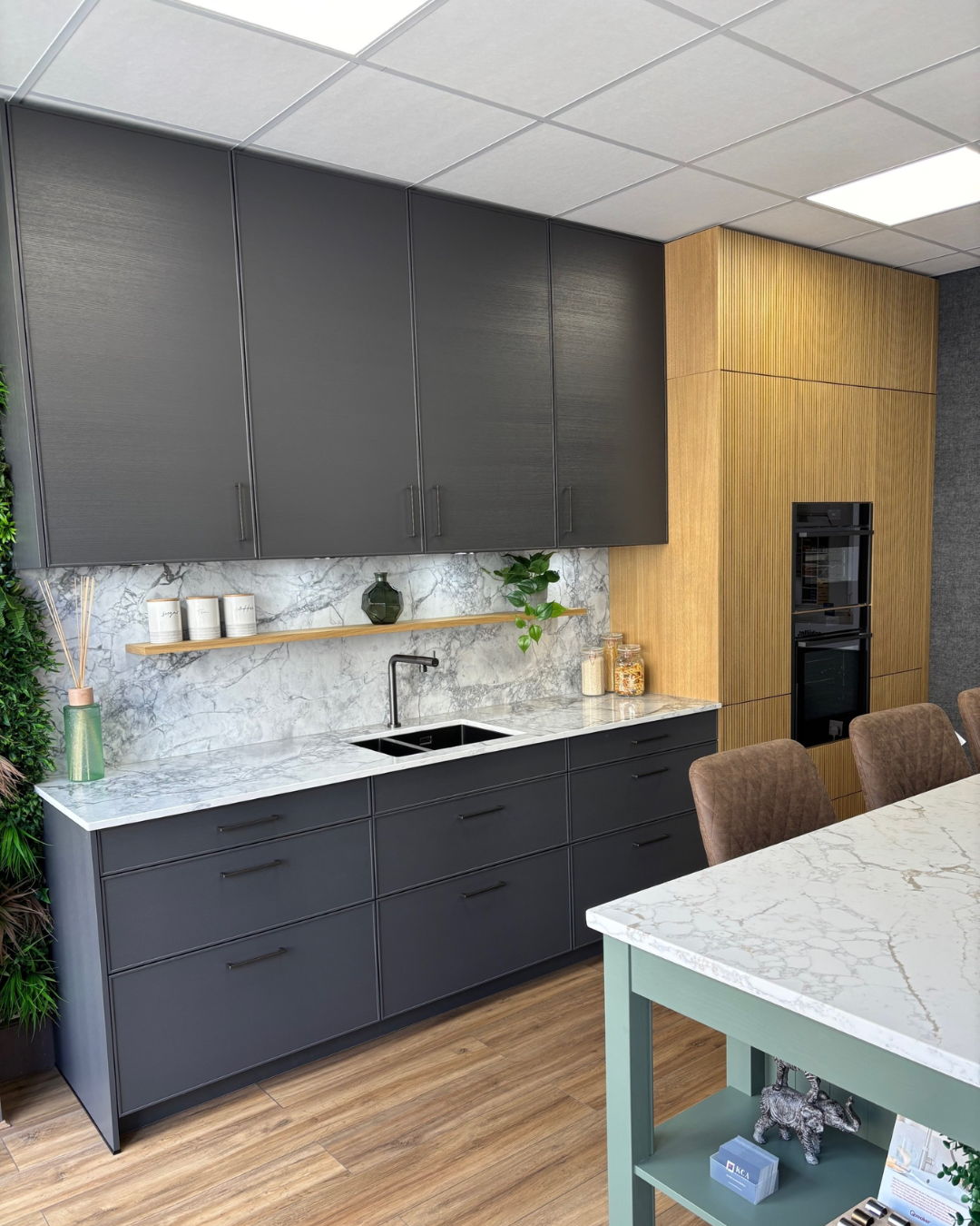 Modern kitchen with grey cabinets, marble effect countertops, and wooden accents.
