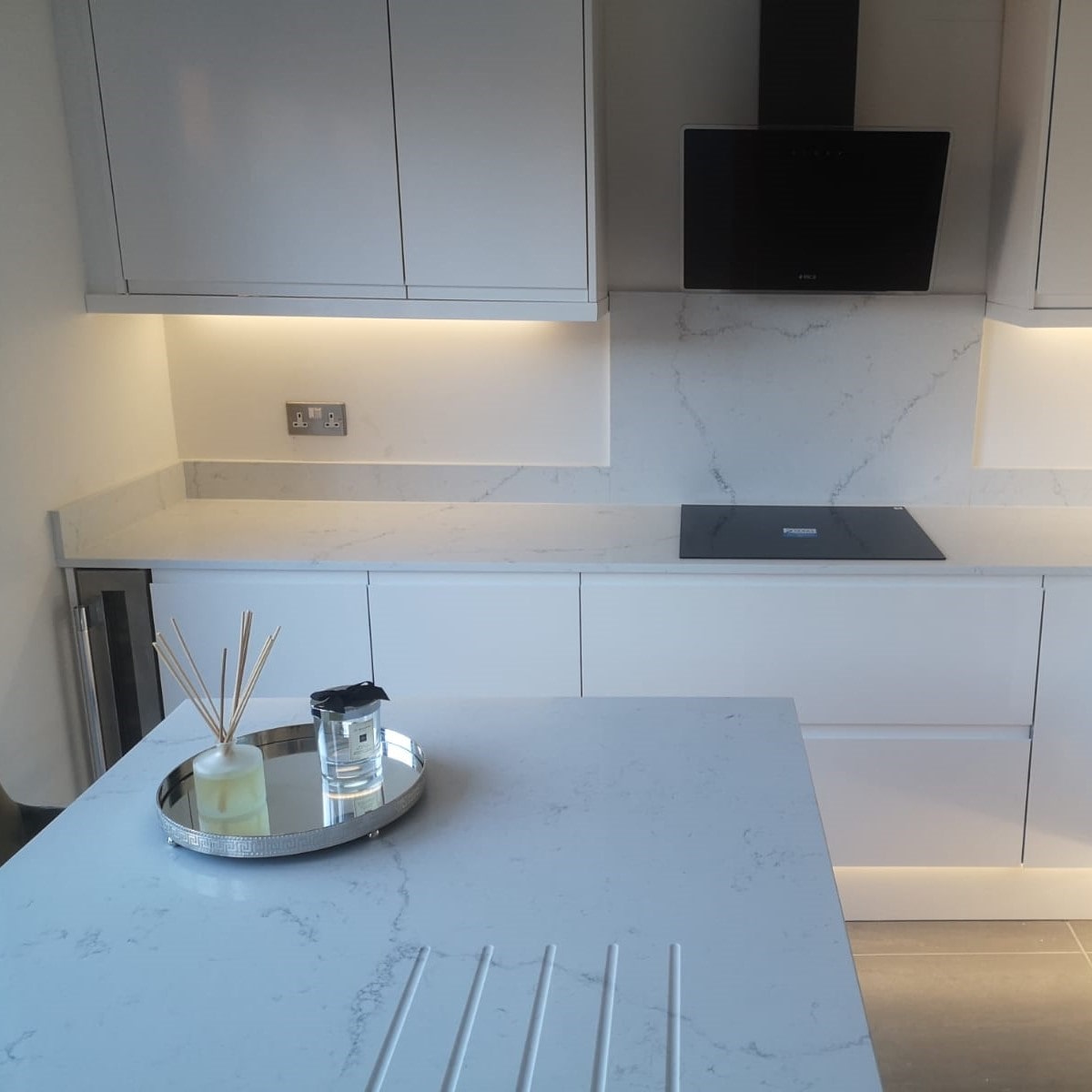 Fugen Avalanche soft white Quartz kitchen worktops and backsplash with faint veining in a grey colour.